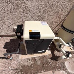 Outdoor pool equipment: a beige cabinet pump/heat unit on a concrete pad with connected pipes and a filter beside it against a stucco wall.